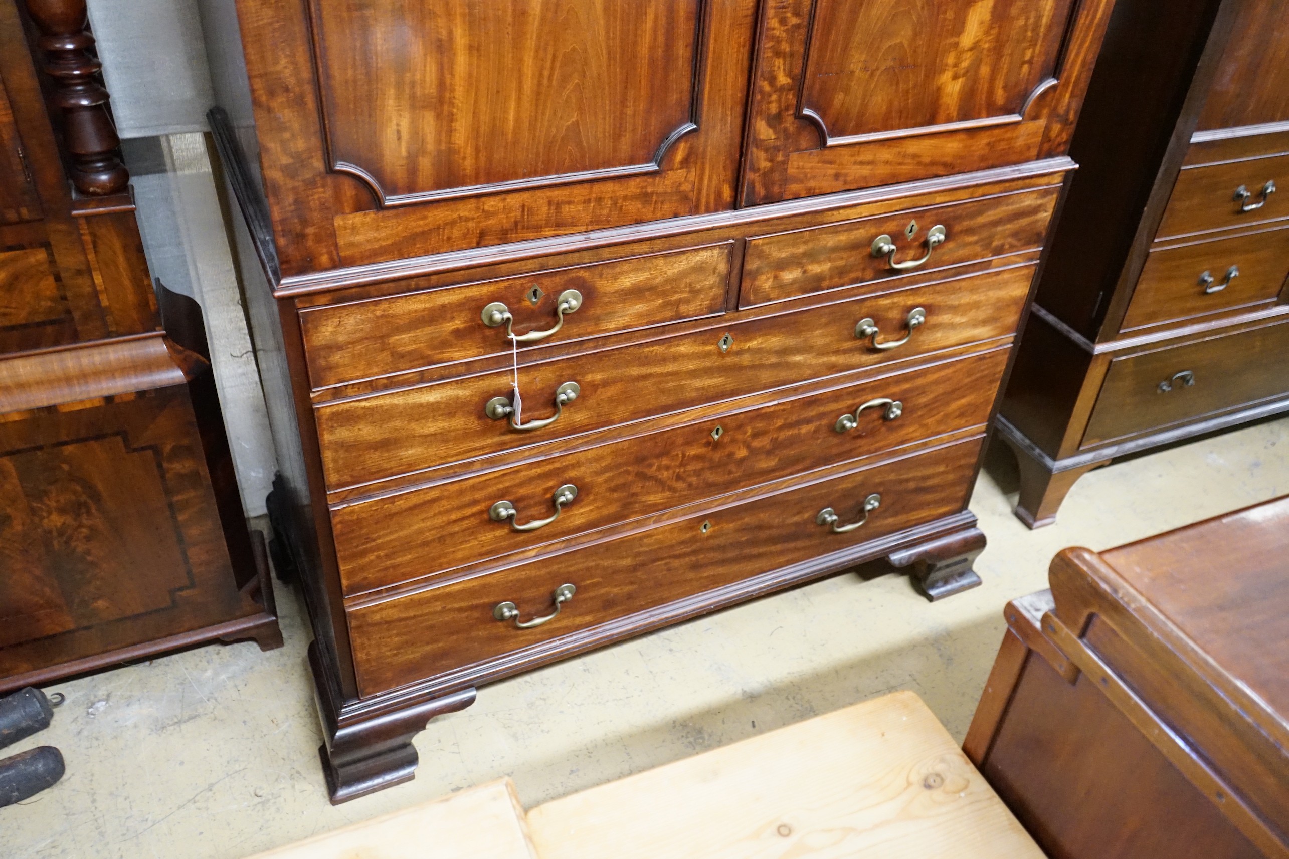 A George III flamed mahogany linen press with broken arch pediment, interior adapted, width 64cm, depth 240cm, height 132cm